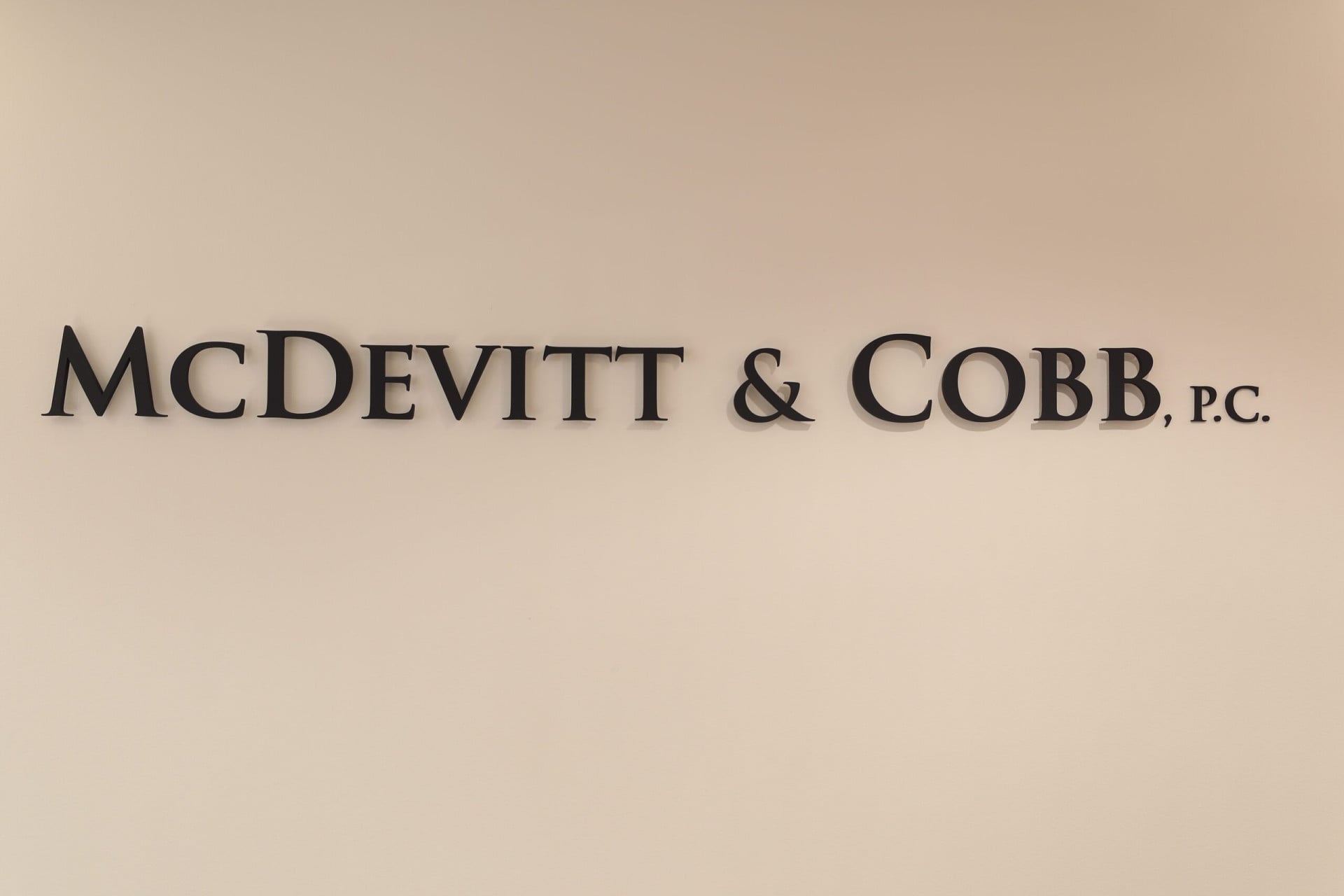 A wall sign reads "McDevitt & Cobb, P.C." in black capital letters on a plain beige background.